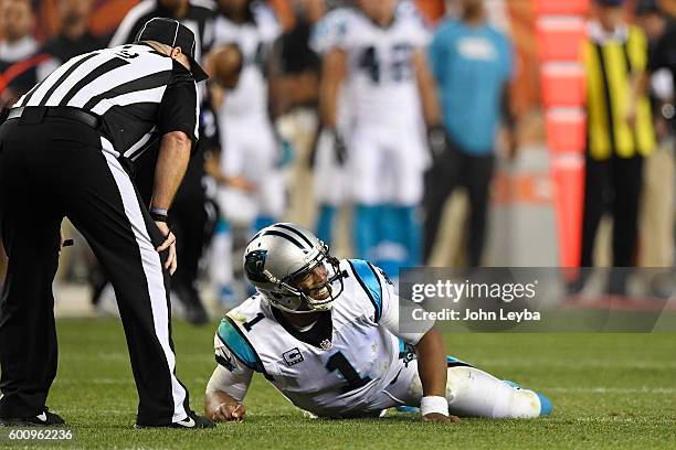Cam Newton of the Carolina Panthers lies on the turf after getting hit hard by Darian Stewart of the Denver Broncos and Shaquil Barrett during the...