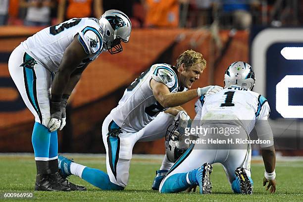 Greg Olsen of the Carolina Panthers and Donald Hawkins check the health of Cam Newton after he was pummeled by Shaquil Barrett of the Denver Broncos...