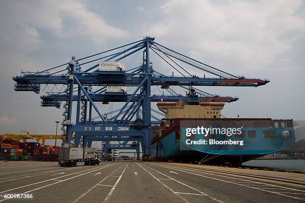 An A.P. Moeller-Maersk A/S branded cargo ship sits moored next to gantry cranes at a container terminal at Busan New Port in Busan, South Korea, on...