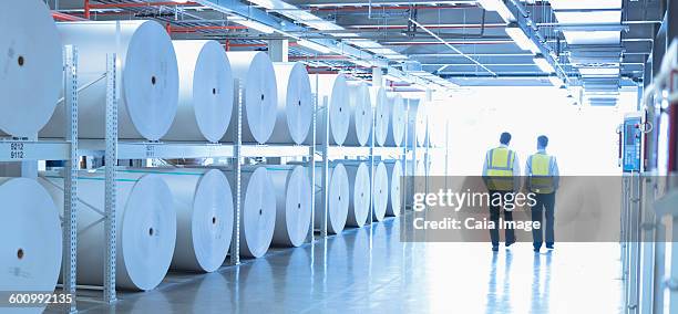 workers in reflective clothing walking along large paper spools in printing plant - paper mill stock pictures, royalty-free photos & images