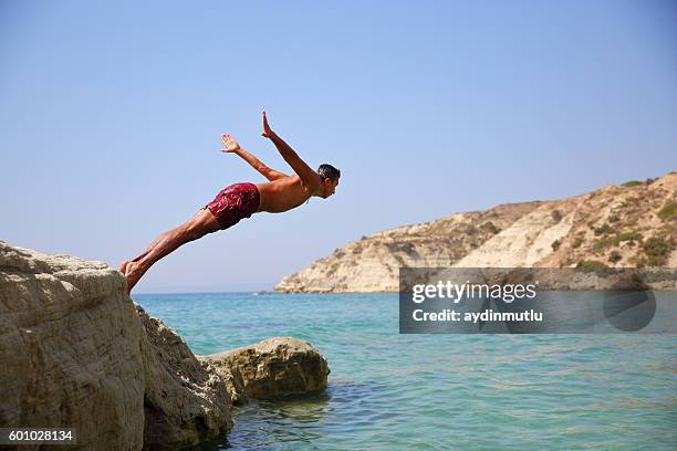 young man diving - salto desde acantilado fotografías e imágenes de stock