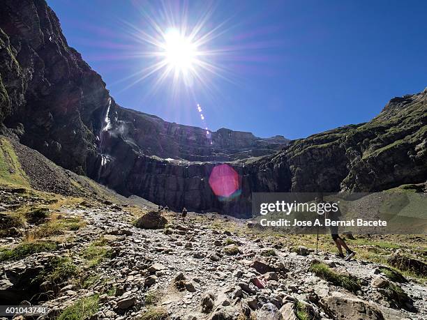 trekkers walking along the cirque of gavarnie . hautes pyrenees. france. world heritage by unesco, the great waterfall - midirock stock pictures, royalty-free photos & images