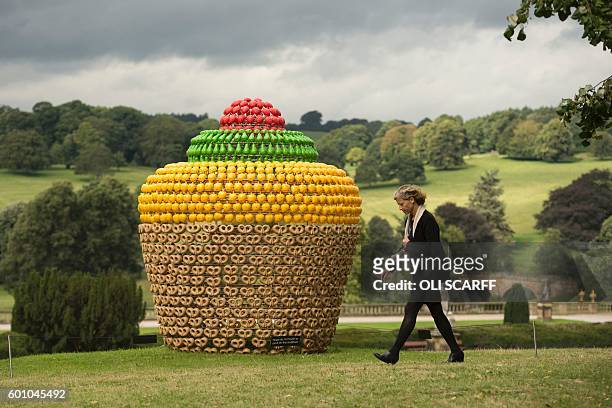 Woman walks past a sculpture by artist Portuguese artist Joana Vasconcelos entitled 'Fruitcake' that features in the 'Beyond Limits' exhibition in...