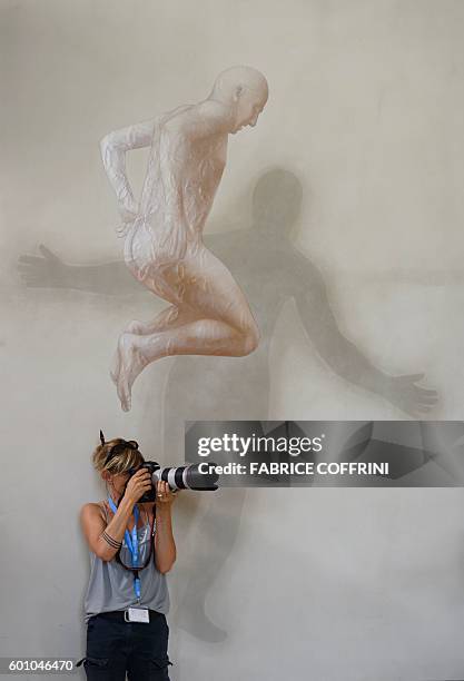 News photographer operates in front of a painting during a press briefing following a meeting of the International Syria Support Group's Humanitarian...