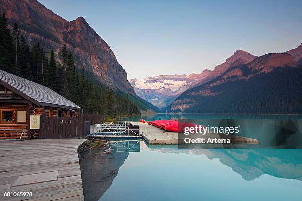 Red canoes at glacial Lake Louise with Victoria glacier, Banff National Park, Alberta, Canada.