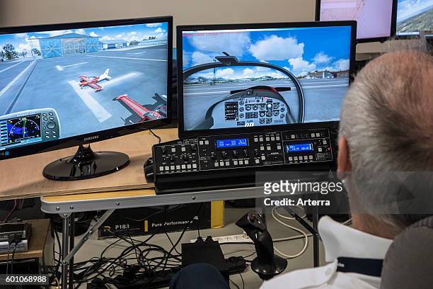 Man navigating virtual airplane in amateur flight simulator.