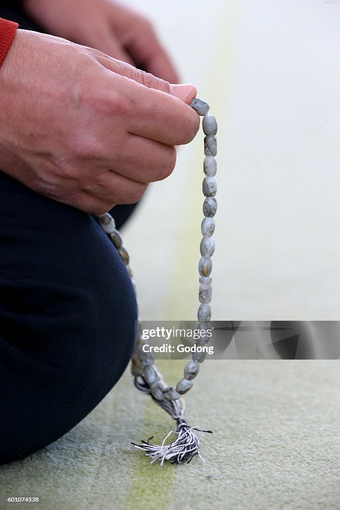 Man praying in a mosque. Tasbih (prayer beads).
