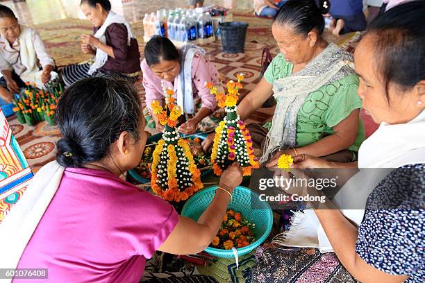 Pagoda. Women preparing flower offerings for a buddhist ceremony. Kasi, Laos.