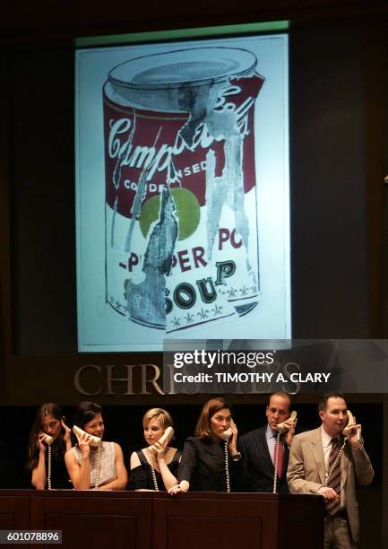 Christie's phone bid takers stand in front of a video screen showing Andy Warhol's "Small Torn Campbell's Soup Can" during Christie's New York...