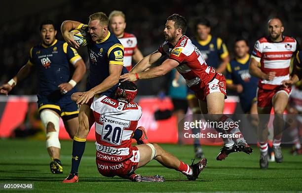 Warriors player Perry Humphreys breaks the tackle of Jacob Rowan and Greig Laidlaw of Gloucester during the Aviva Premiership match between Worcester...