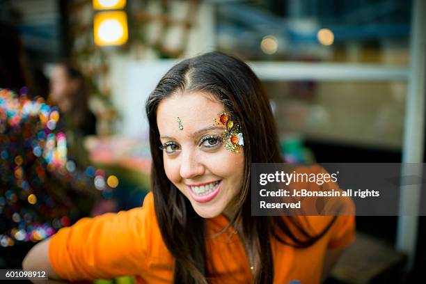 woman with glitter on her face smiling - jc bonassin stock-fotos und bilder