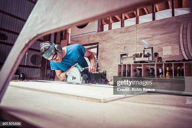 an adult, male carpenter working with power tools in his wood shop - schreiner stock-fotos und bilder