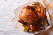 baked whole chicken with oranges on plate. horizontal top view
