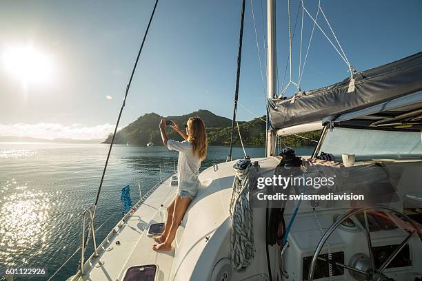 woman on sailing boat photographing landscape with mobile phone - whitsundayeilanden stockfoto's en -beelden