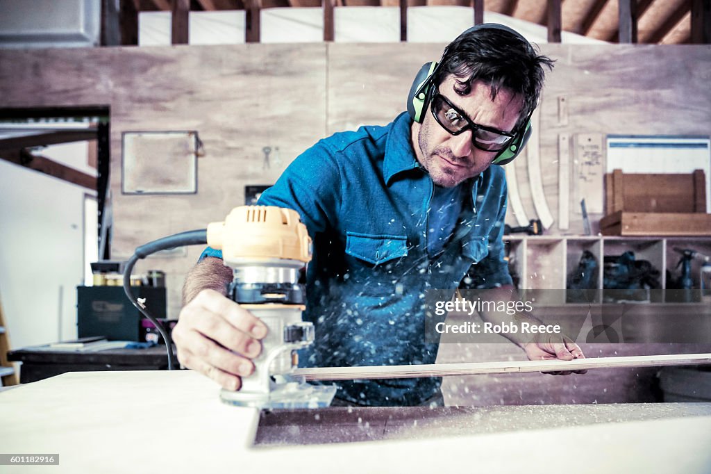 An adult, male carpenter working with tools in his wood shop