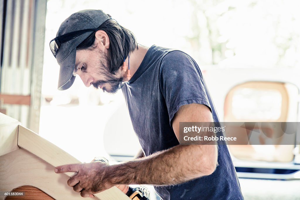 An adult, male carpenter working with tools in his wood shop