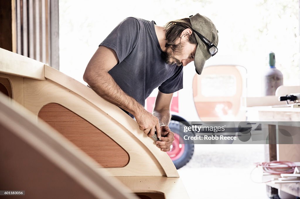 An adult, male carpenter working with tools in his wood shop