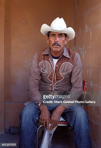 Portrait of a man in blue jeans, a brown western shirt, and a white cowboy hat, Juarez, Mexico, late 1980s.
