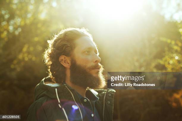 man standing in sunlight in forest - barba peluria del viso foto e immagini stock