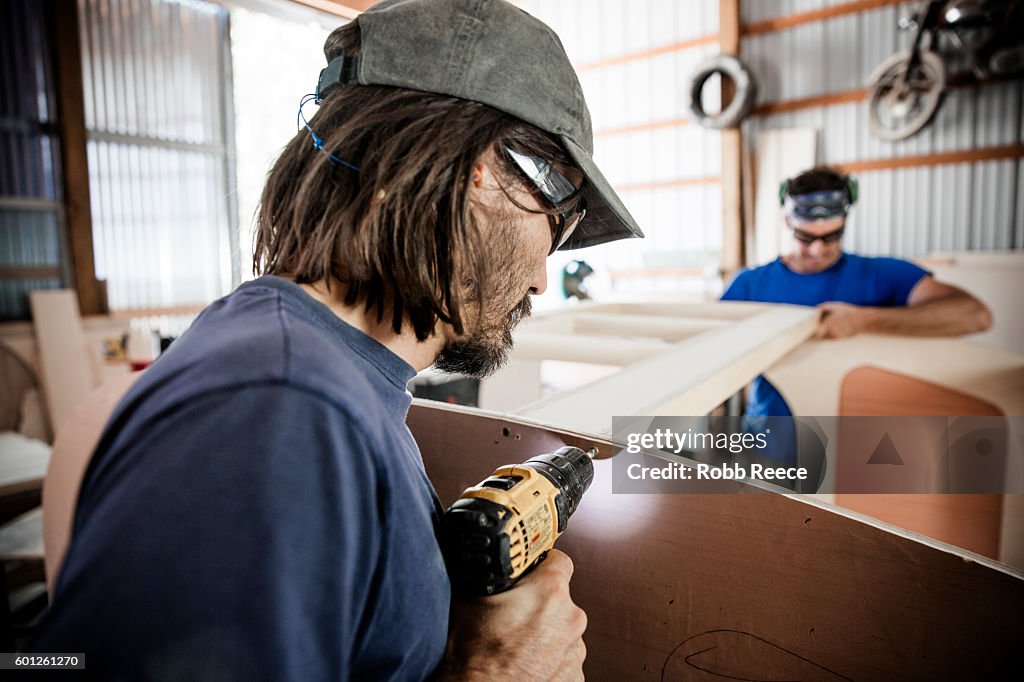 Two adult, male carpenters working with tools in a wood shop