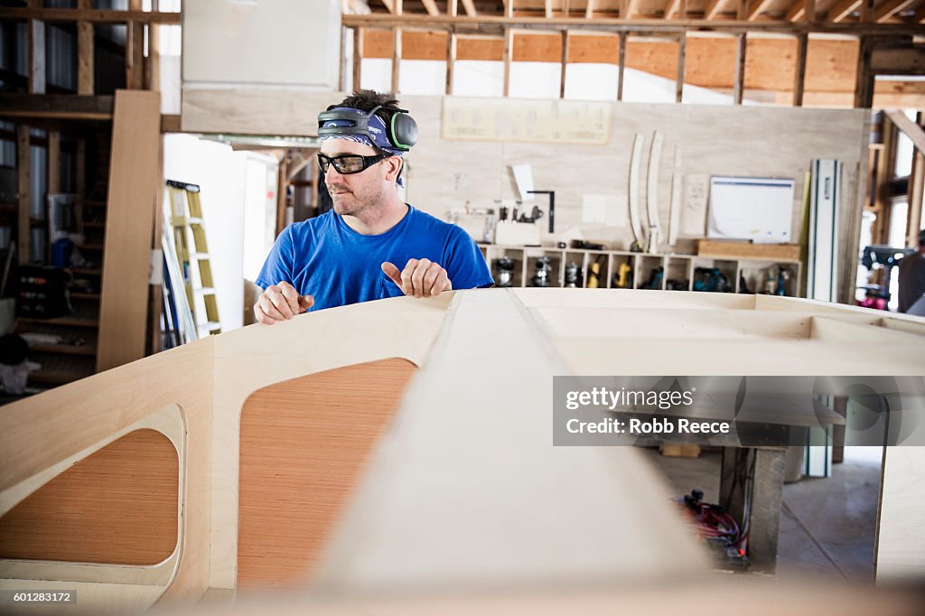 An adult, male carpenter working in his wood shop