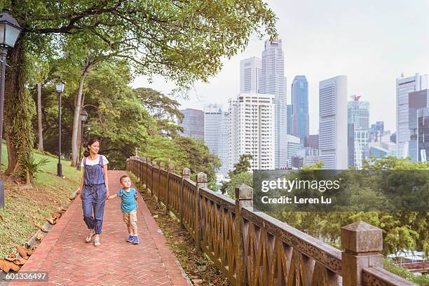 mother and kid walking on alley at park - singapore alley stock pictures, royalty-free photos & images