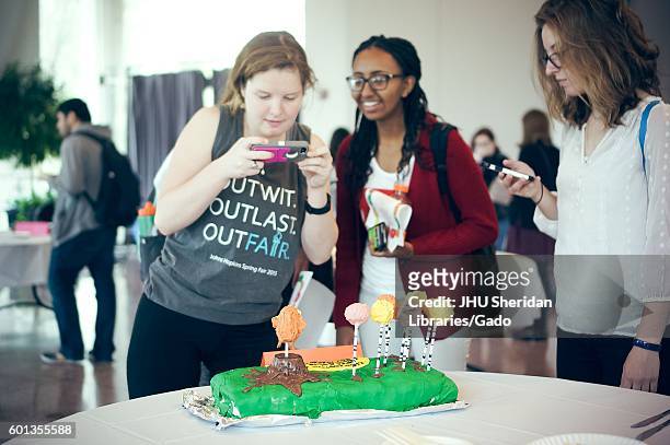 Undergraduate students taking pictures of a cake decorated for "The Lorax" at the Edible Book Festival at Johns Hopkins University, Baltimore,...