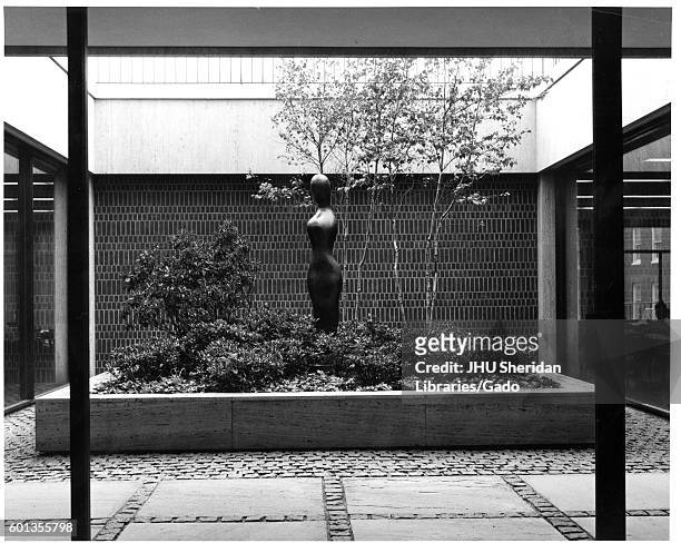 View of internal courtyard, with a sculpture and landscaped trees and shrubbery, in the Milton S Eisenhower library of Johns Hopkins University, in...