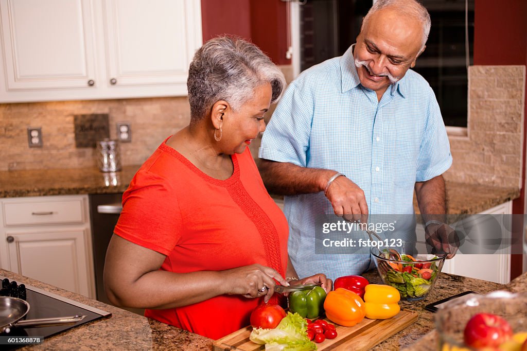 Feliz pareja de adultos mayores cocinando juntos en la cocina de casa.