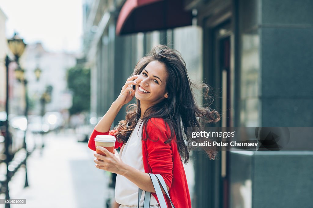 Cheerful girl with phone on the street looking back