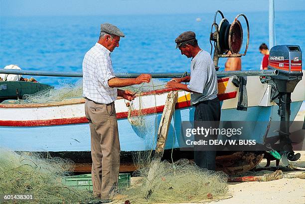 Fishermen and fishing boat on the beach, Armacao De Pera, Algarve, Portugal.