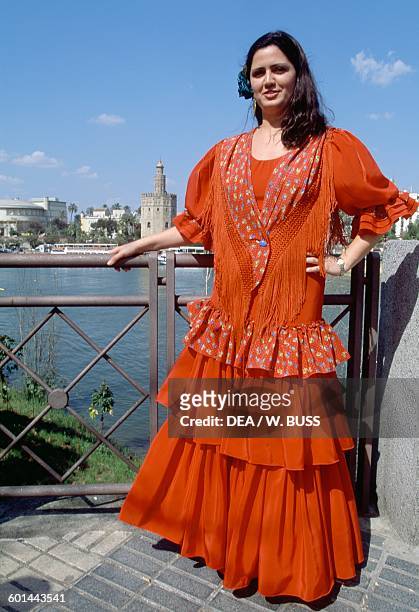 Young woman in traditional costume during the Feria de Abril , with the Gold Tower in the background, 12th century, Seville, Andalusia, Spain.