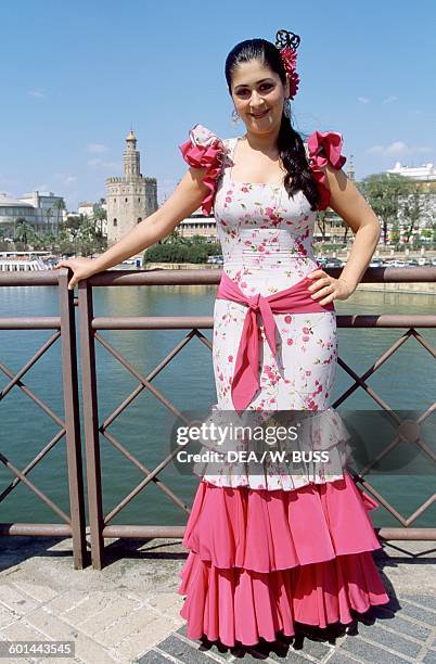 Young woman in traditional costume during the Feria de Abril , with the Gold Tower in the background, 12th century, Seville, Andalusia, Spain.