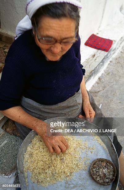 Elderly woman separating the mastic by size, Pyrgi, Chios island, Greece.