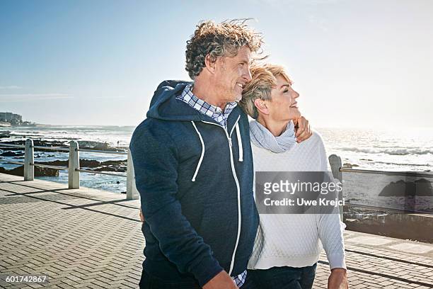 senior couple walking on promenade - man walking side view stock pictures, royalty-free photos & images
