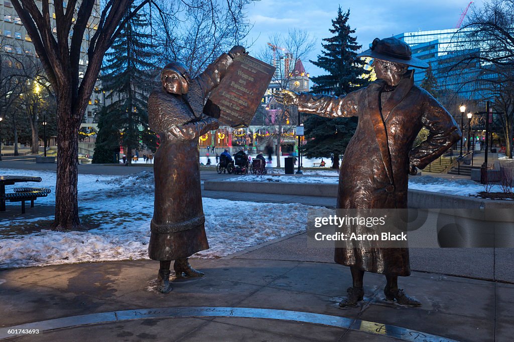 Two metal statues of women in a park
