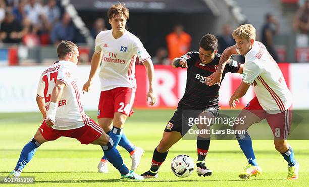 Chicharito of Leverkusen is challenged by Nicolai Mueller, Gotoku Sakai and Lewis Holtby of Hamburg during the Bundesliga match between Bayer 04...