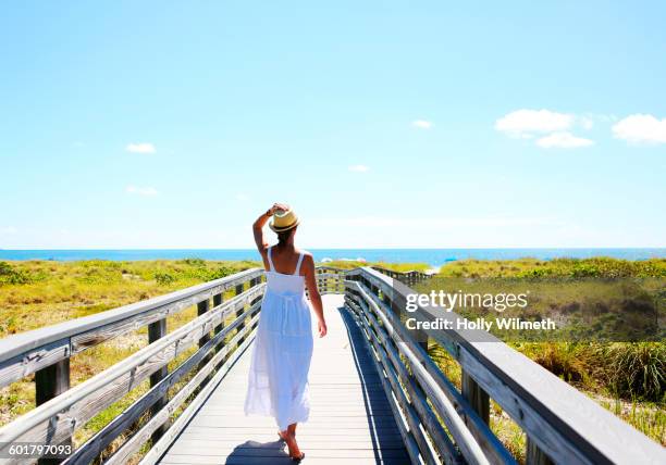 caucasian woman on wooden walkway to beach - walking boardwalk stock pictures, royalty-free photos & images
