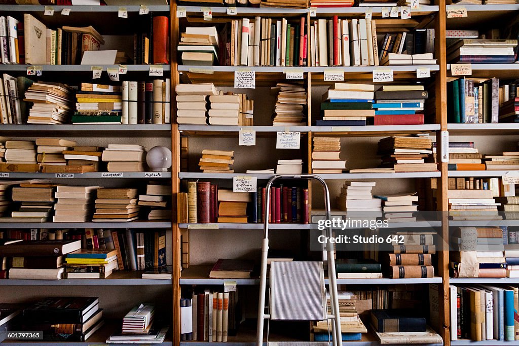 Stepladder by bookshelves in library