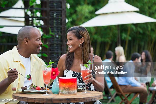 couple drinking cocktails at restaurant patio - black couple dining stockfoto's en -beelden