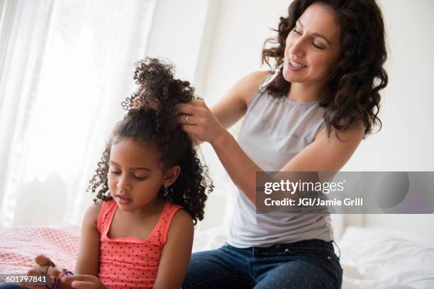 mother styling hair of daughter - combing foto e immagini stock