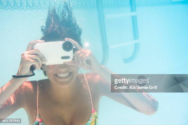 caucasian woman using underwater camera in swimming pool - macchina fotografica subacquea foto e immagini stock