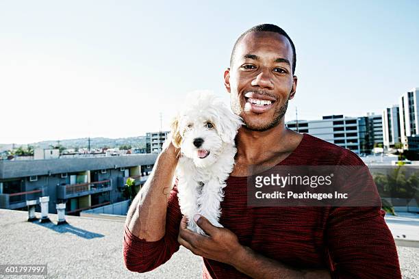 african american man holding dog on urban rooftop - pet heaven stock pictures, royalty-free photos & images