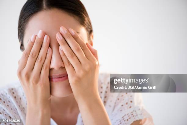 hispanic woman covering her eyes - augen zuhalten stock-fotos und bilder