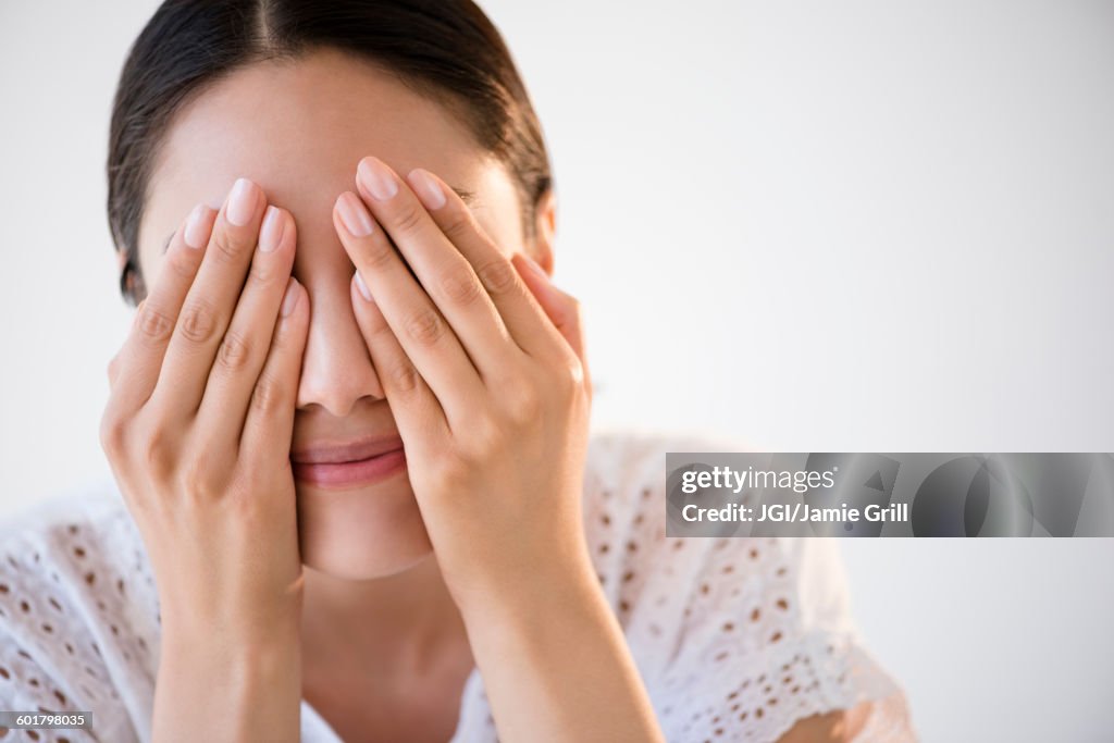 Hispanic woman covering her eyes