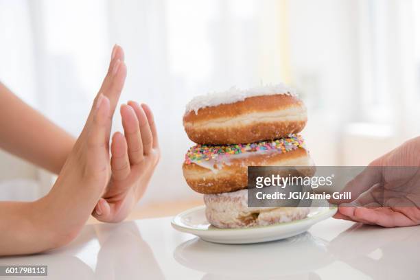 woman refusing plate of donuts - temptation stock pictures, royalty-free photos & images