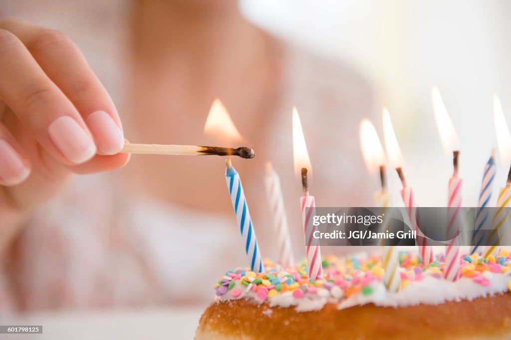 Hispanic woman lighting birthday candles