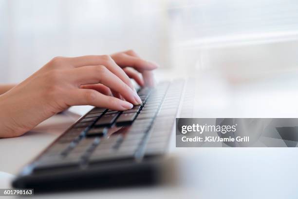 hispanic businesswoman typing on keyboard - teclado de computador fotografías e imágenes de stock