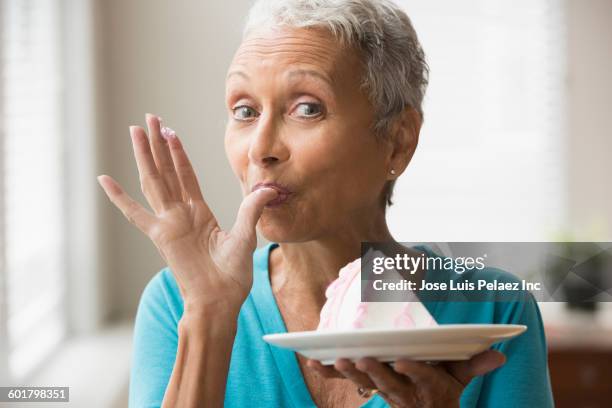 mixed race woman eating cake - senior adult eating stock pictures, royalty-free photos & images