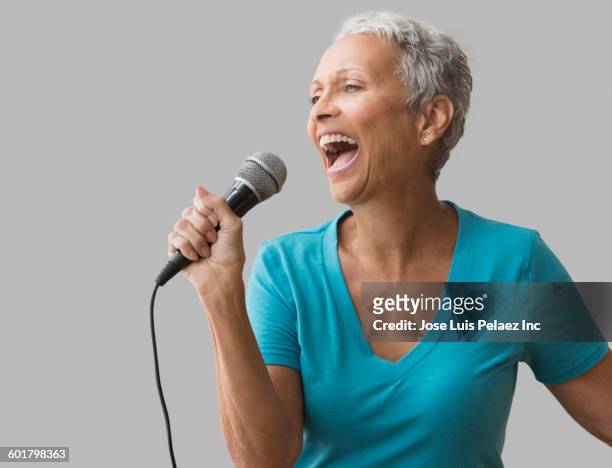 mixed race woman singing with microphone - singer microphone stock pictures, royalty-free photos & images